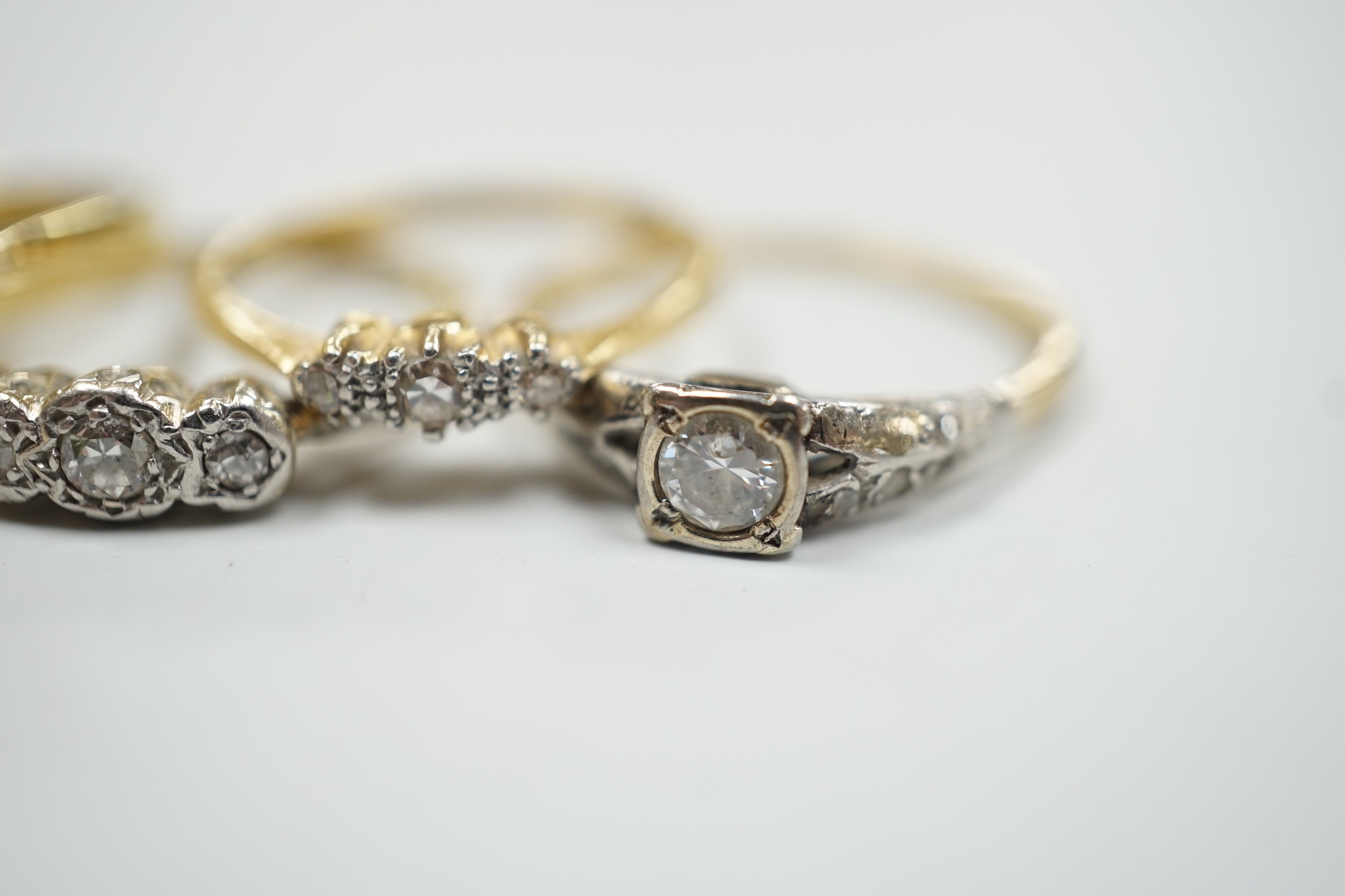 Four assorted 18ct and gem set dress rings, including white opal and diamond and two three stone diamond and one yellow metal and single stone diamond set ring, gross weight 14.3 grams.